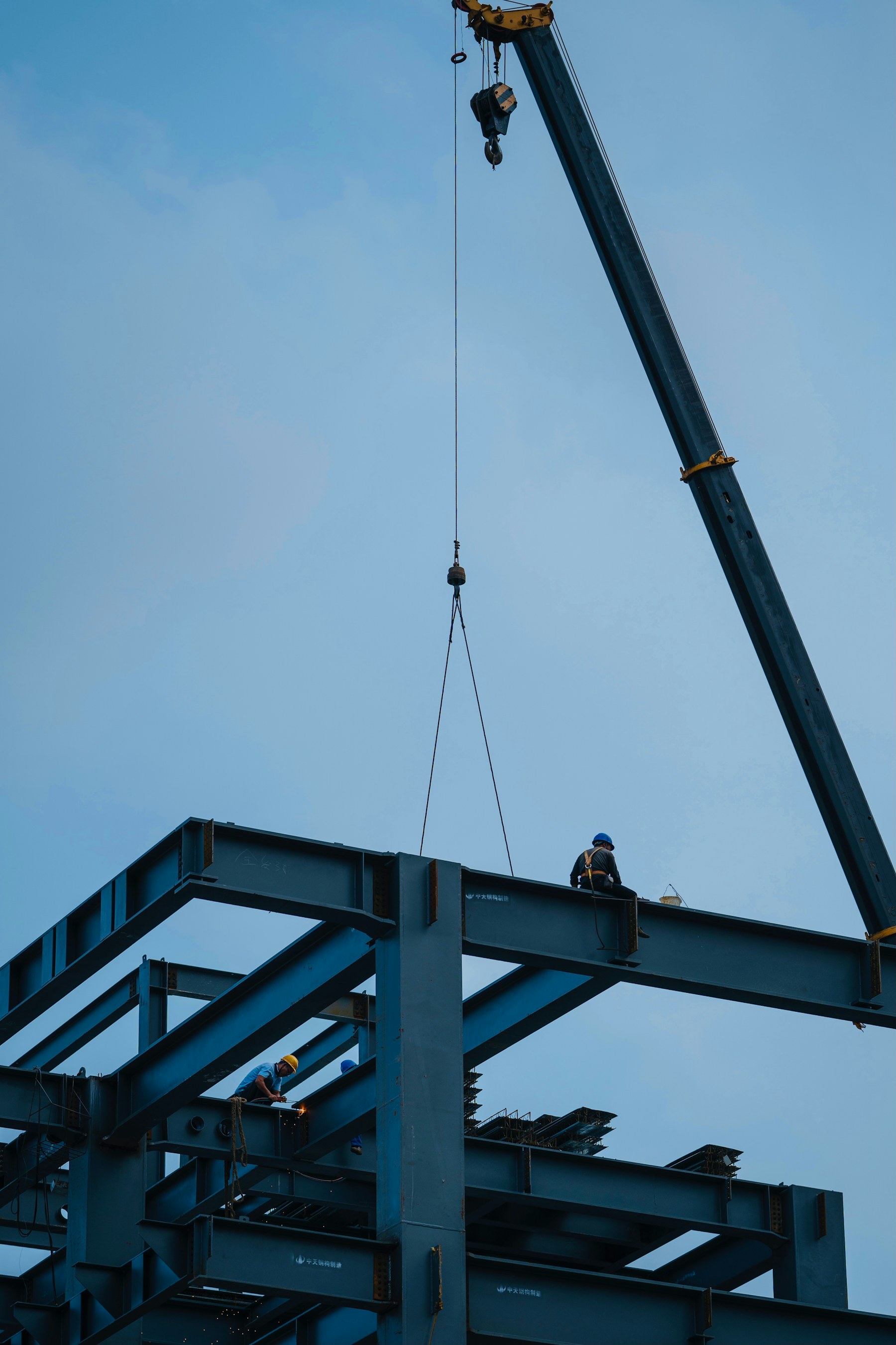 Steel construction workers and crane assembling a building structure